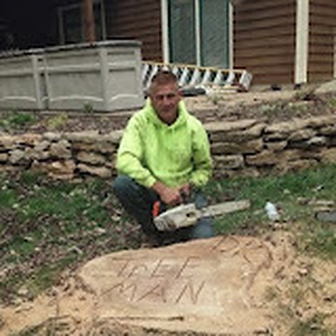 Don Kottman kneeling beside a freshly cut stump