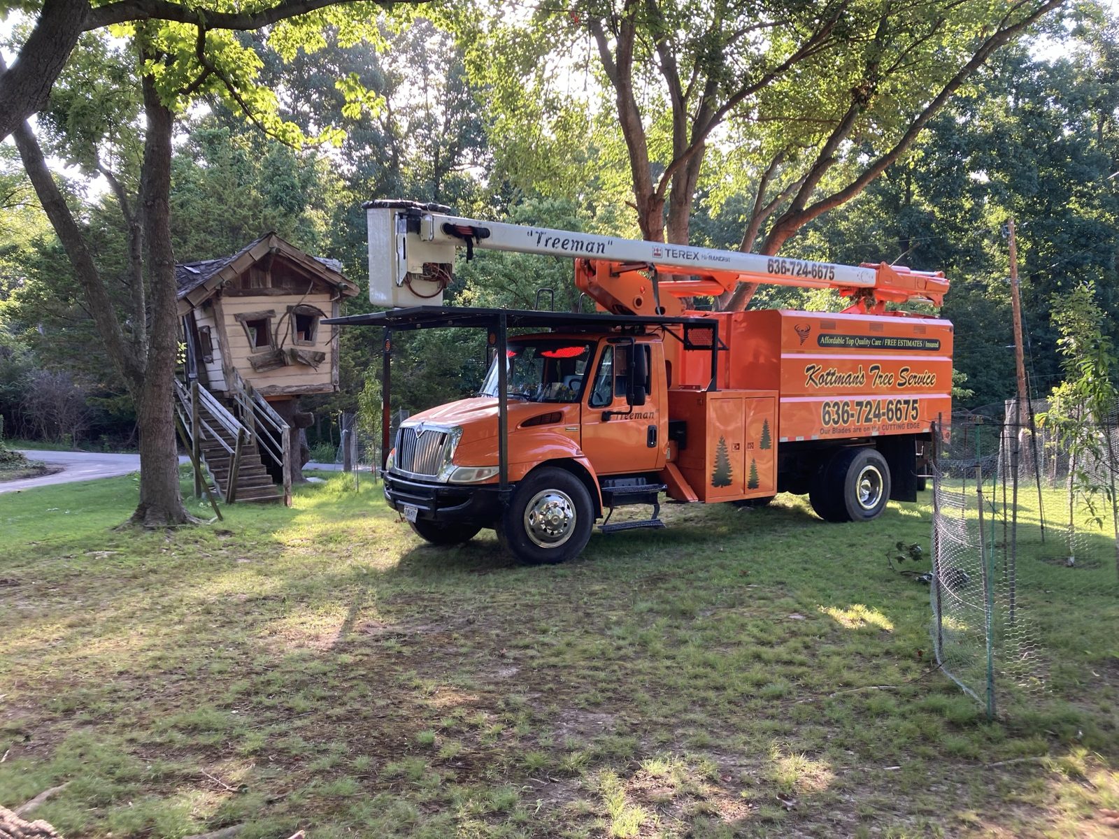 The orange Kottman's Treeman bucket truck parked on a job